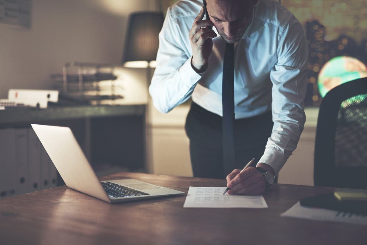 bilde av revisor som snakker i mobilen og skriver på et papir.
