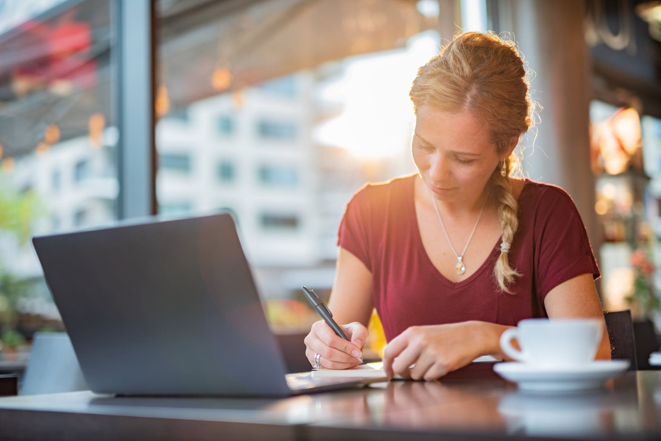 Bilde av en kvinne med kaffe og laptop som fyller ut skattemelding med næringsspesifikasjon for sitt enkeltpersonforetak.
